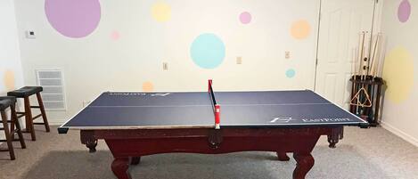 Une table de billard dans une pièce dont le mur blanc est décoré de cercles colorés.