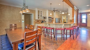 A spacious kitchen with a large island, wooden chairs, and a dining table. - Spacious Stallion Lake Ranch Home w/ Patio (Lindale)