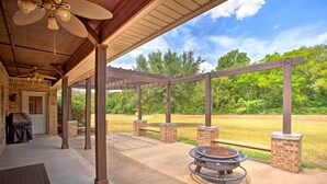 A covered patio with a grill, a ceiling fan, and a view of a grassy field. - Spacious Stallion Lake Ranch Home w/ Patio (Lindale)
