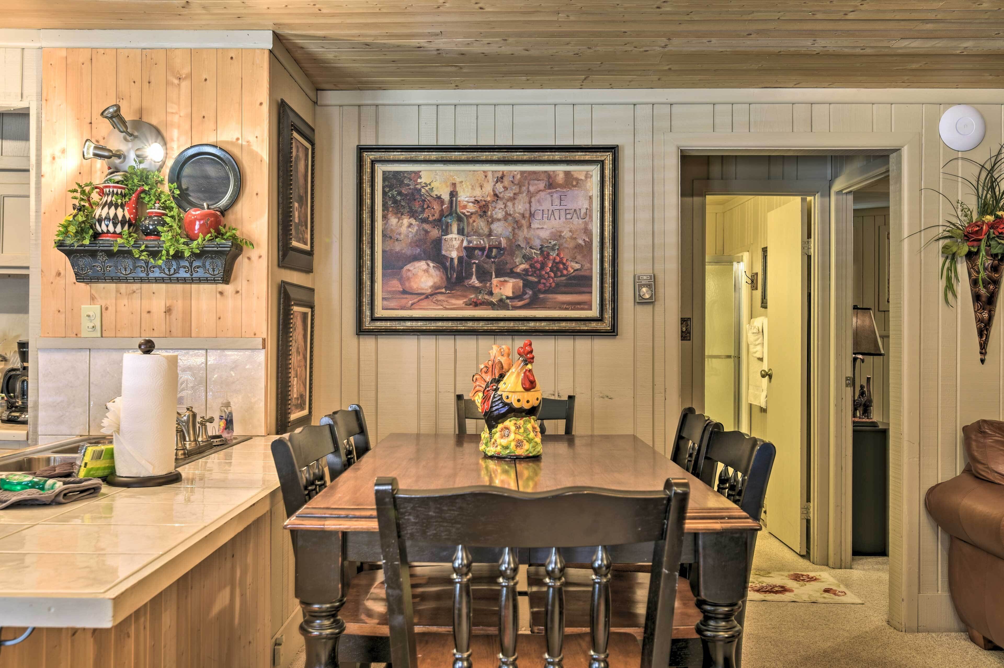 A dining area with a wooden table, chairs, and a painting above.