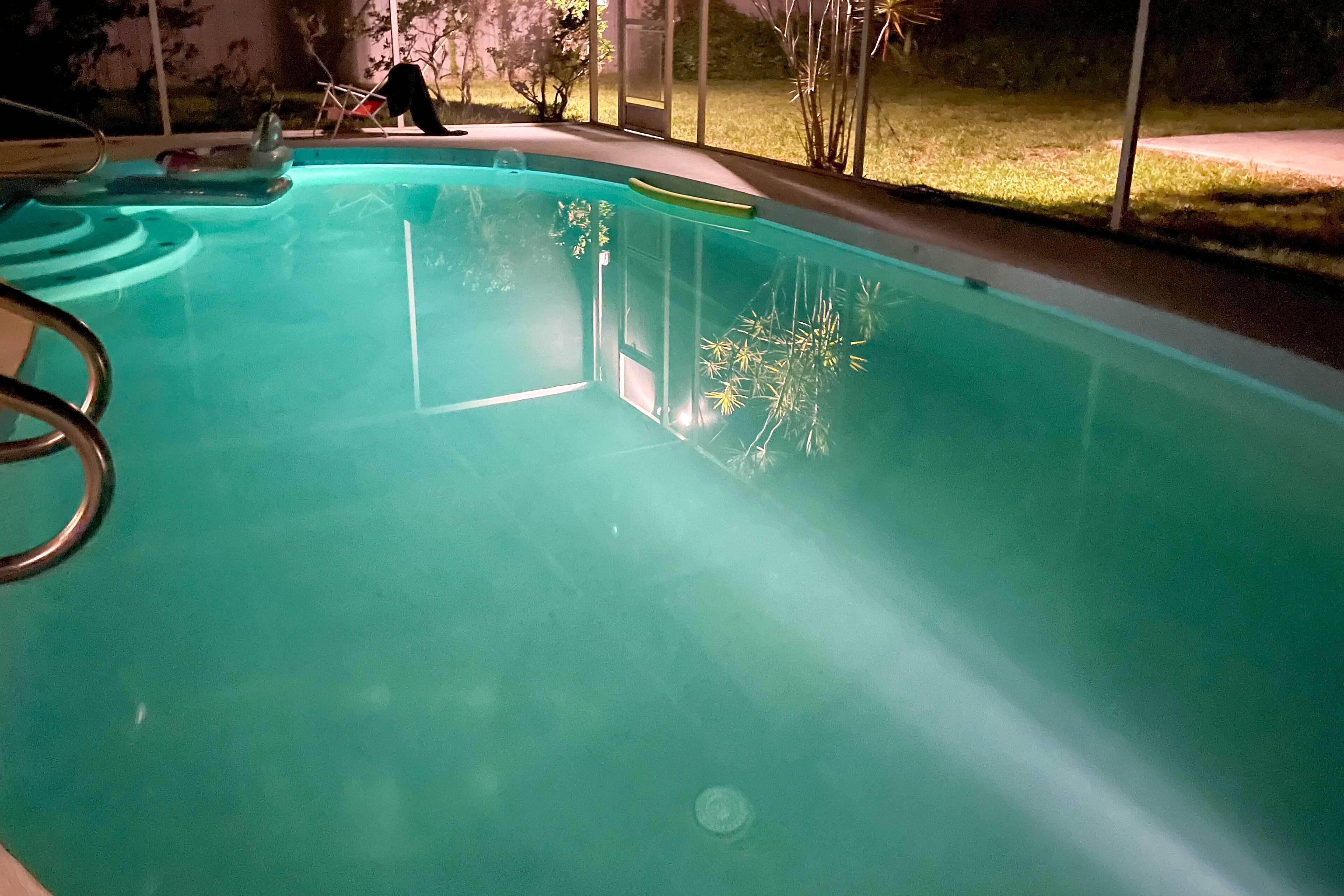 A swimming pool with clear water, a diving board, and a view of the surrounding area.