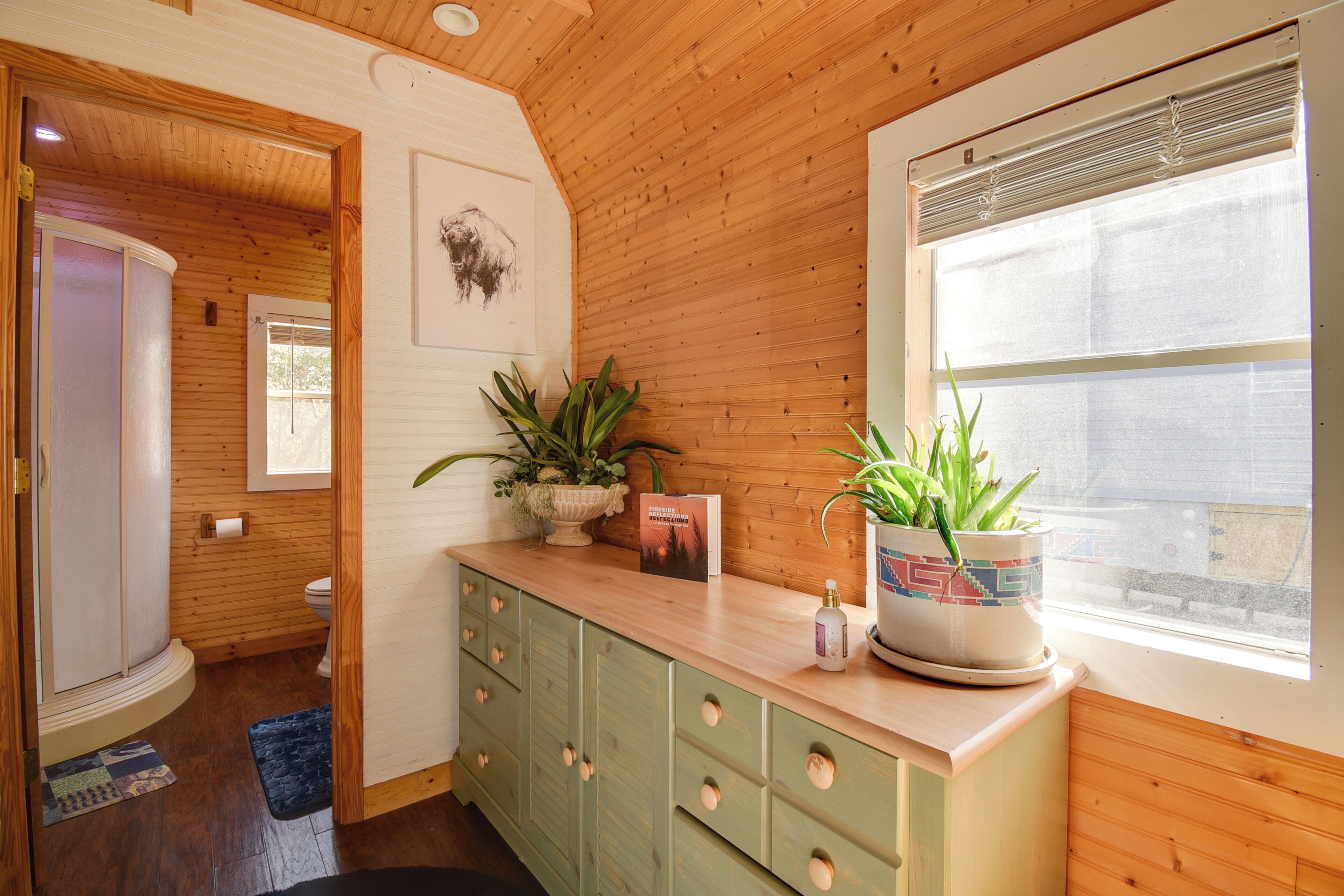 A wooden interior with a kitchen counter, cabinets, and a window with blinds.