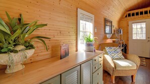 A wooden interior with a wooden ceiling, a wicker chair, a potted plant, and a white door. - Cozy Calabash Studio ~ 4 Mi to Sunset Beach! (Sunset Beach)