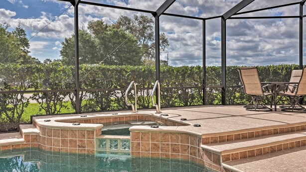 A hot tub area with steps leading into the water, surrounded by a covered patio with chairs and a table. - The Aviator's Dream: Pool, Spa & Private Runway! (Port Orange)