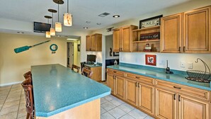 A kitchen with wooden cabinets, a blue countertop, and pendant lighting. - The Aviator's Dream: Pool, Spa & Private Runway! (Port Orange)