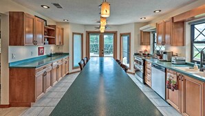 A spacious kitchen with wooden cabinets, a long countertop, and a central island. - The Aviator's Dream: Pool, Spa & Private Runway! (Port Orange)