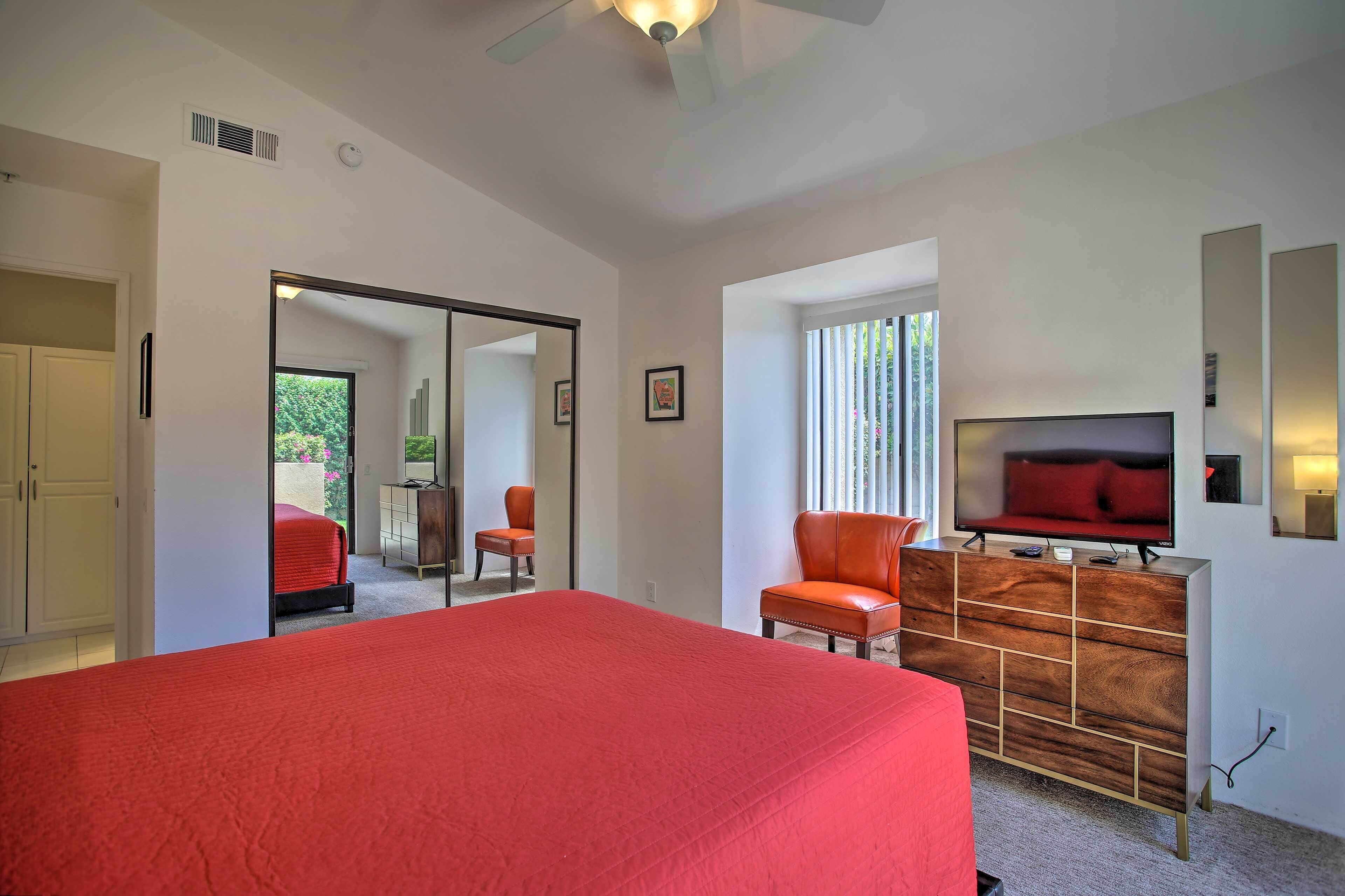 A bedroom with a large bed, a TV, a dresser, and a chair.