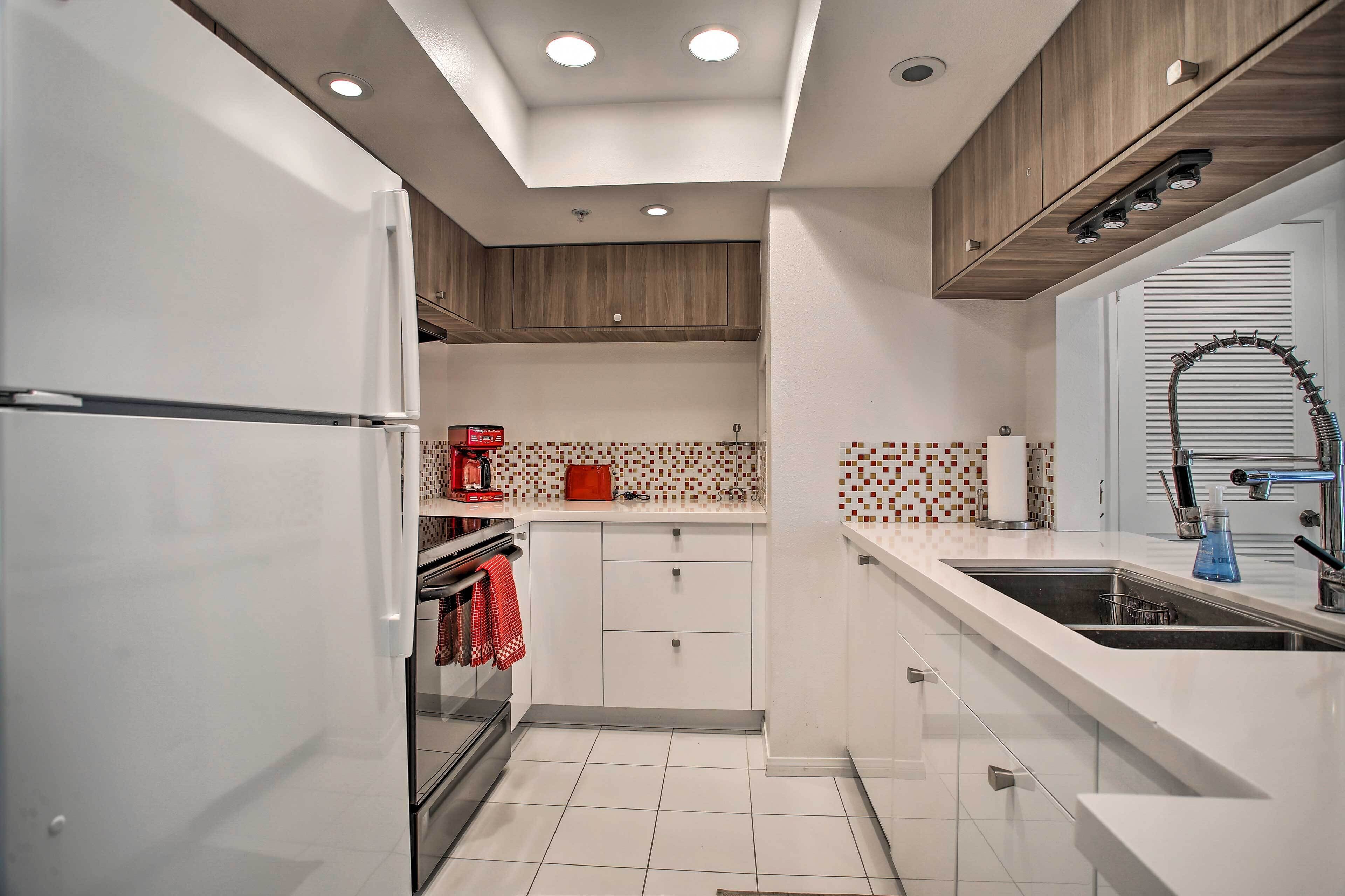 A modern kitchen with white cabinetry, a built-in oven, a coffee maker, and a sink with a faucet.