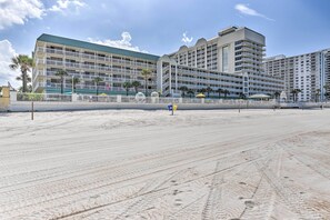 Un hôtel situé en bord de mer, doté de nombreux balcons, d’un espace piscine et de palmiers.