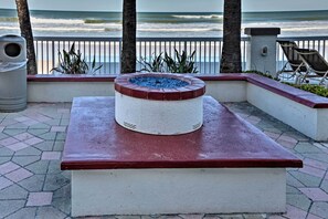 A stone bench with a white and red design, overlooking a beach with palm trees and a railing. - Ocean-view Daytona Beach Resort Retreat w/ Balcony (Daytona Beach)