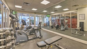 Ein Fitnessstudio mit Cardiogeräten, Gewichtbänken und einer Spiegelwand.