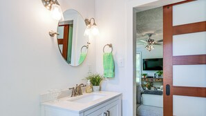 A bathroom with a white vanity, a round mirror, and two wall-mounted lights. - 1 Mi to Dtwn: Family-friendly Brenham Bungalow! (Brenham)