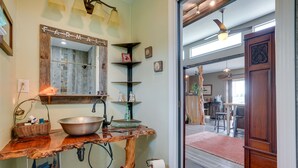 Ein rustikales Badezimmer mit einem Holzbadezimmer-Möbel, einem großen Spiegel und einem Spülbecken im Bauernhausstil.