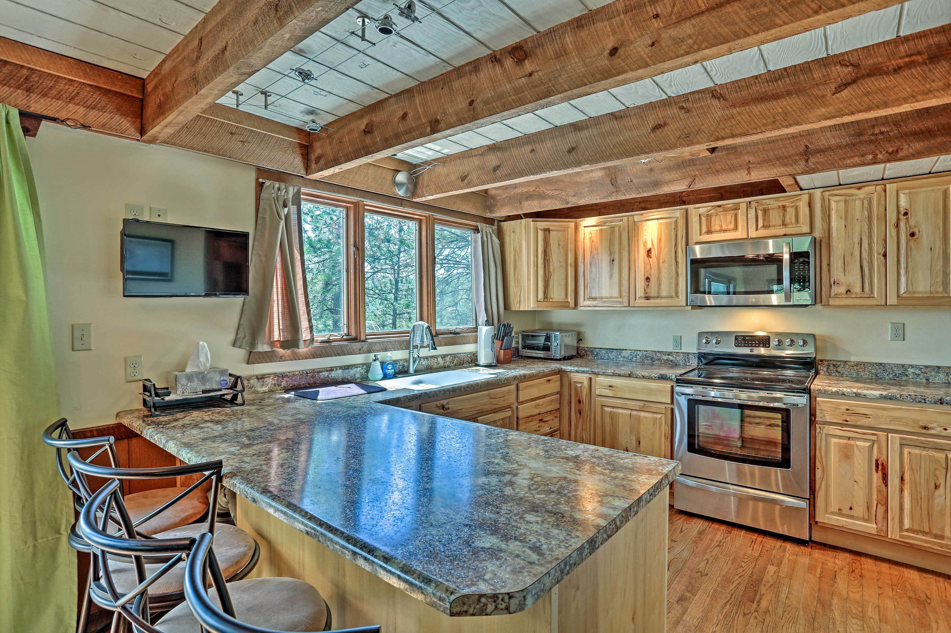 A kitchen with wooden cabinets, a granite countertop, a stainless steel oven, and a microwave.