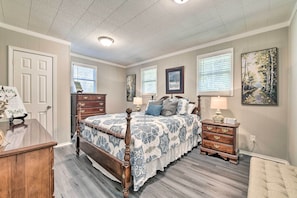 A bedroom with a wooden bed, a dresser, a nightstand, and a chair. - Charming Yadkin Valley Cottage w/ Deck & Yard (Yadkinville)