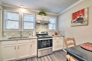 A kitchen with white cabinets, a stainless steel stove, and a black countertop. - Charming Yadkin Valley Cottage w/ Deck & Yard (Yadkinville)