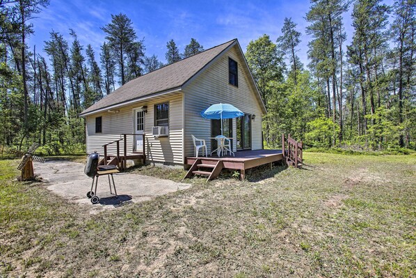 A single-story cabin with a porch, a blue umbrella, and a grill. - Secluded Irons Cabin w/ 5-acre Yard, Deck, Grill! (Irons)