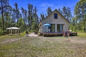 Una cabaña con terraza, mobiliario exterior y un espacio cubierto.