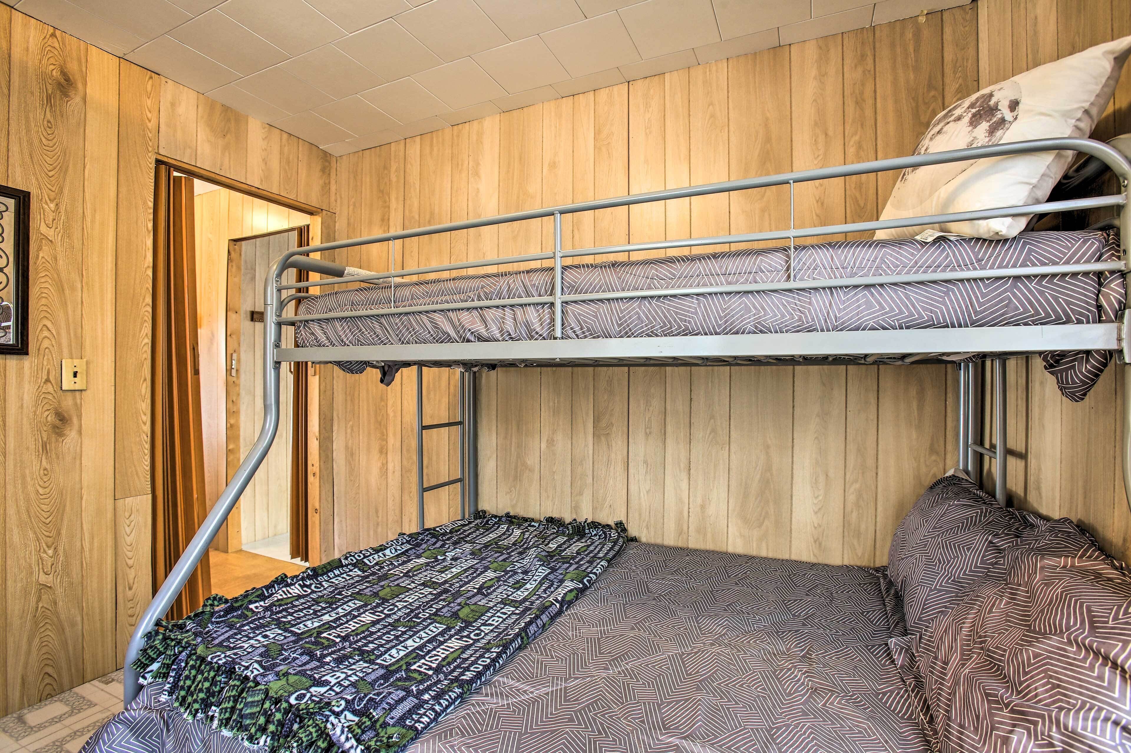 Un lit superposé avec une literie à motifs, des murs en bois et une échelle en métal.
