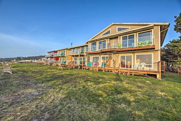A row of wooden houses with balconies, large windows, and a grassy yard.