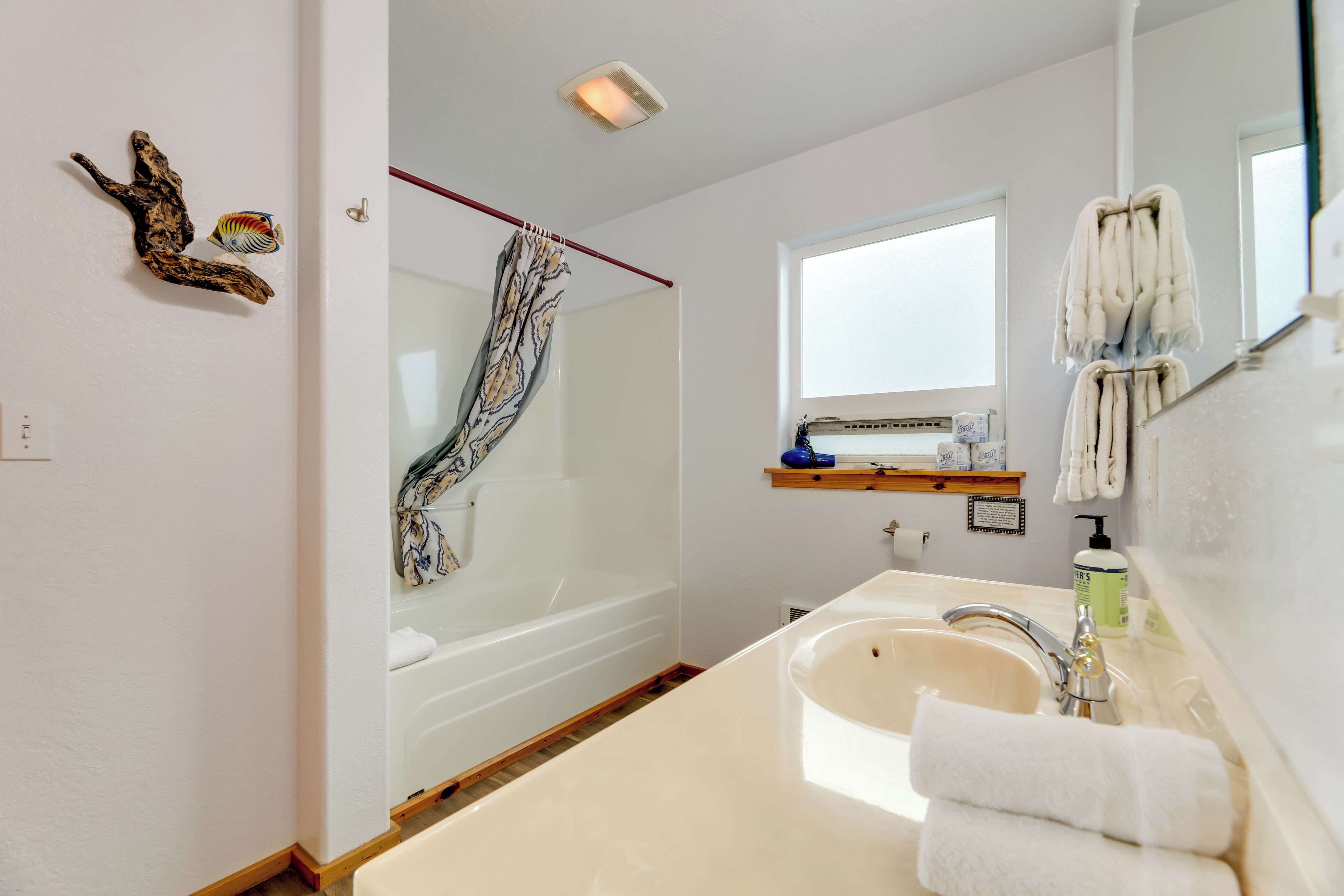 A modern bathroom with a bathtub, a large sink, and a window.