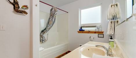 A modern bathroom with a bathtub, a large sink, and a window.