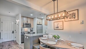 A modern kitchen with a central island, stainless steel appliances, and a dining area with a wooden table and chairs.