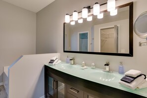 A modern bathroom with a glass sink, a large mirror, and a vanity with a dark cabinet. - Renovated Sunny Port St Lucie Home w/ Outdoor Pool (Port Saint Lucie)