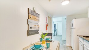 A modern kitchen with white cabinets, a white refrigerator, and a dining area with a table set for two. - Walk to Downtown Albany: Ten Broeck Triangle Apt! (Albany)