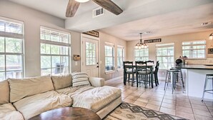 A modern living room with a beige sectional sofa, a wooden coffee table, and a patterned rug. There is a dining area with a wooden table and chairs, and a kitchen area with a bar and island. - Private Fishing Dock: Grand Lake Home (Eucha)