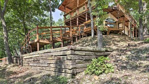 A wooden cabin with multiple levels, built on a hillside with a wooden staircase leading up to it. - Private Fishing Dock: Grand Lake Home (Eucha)