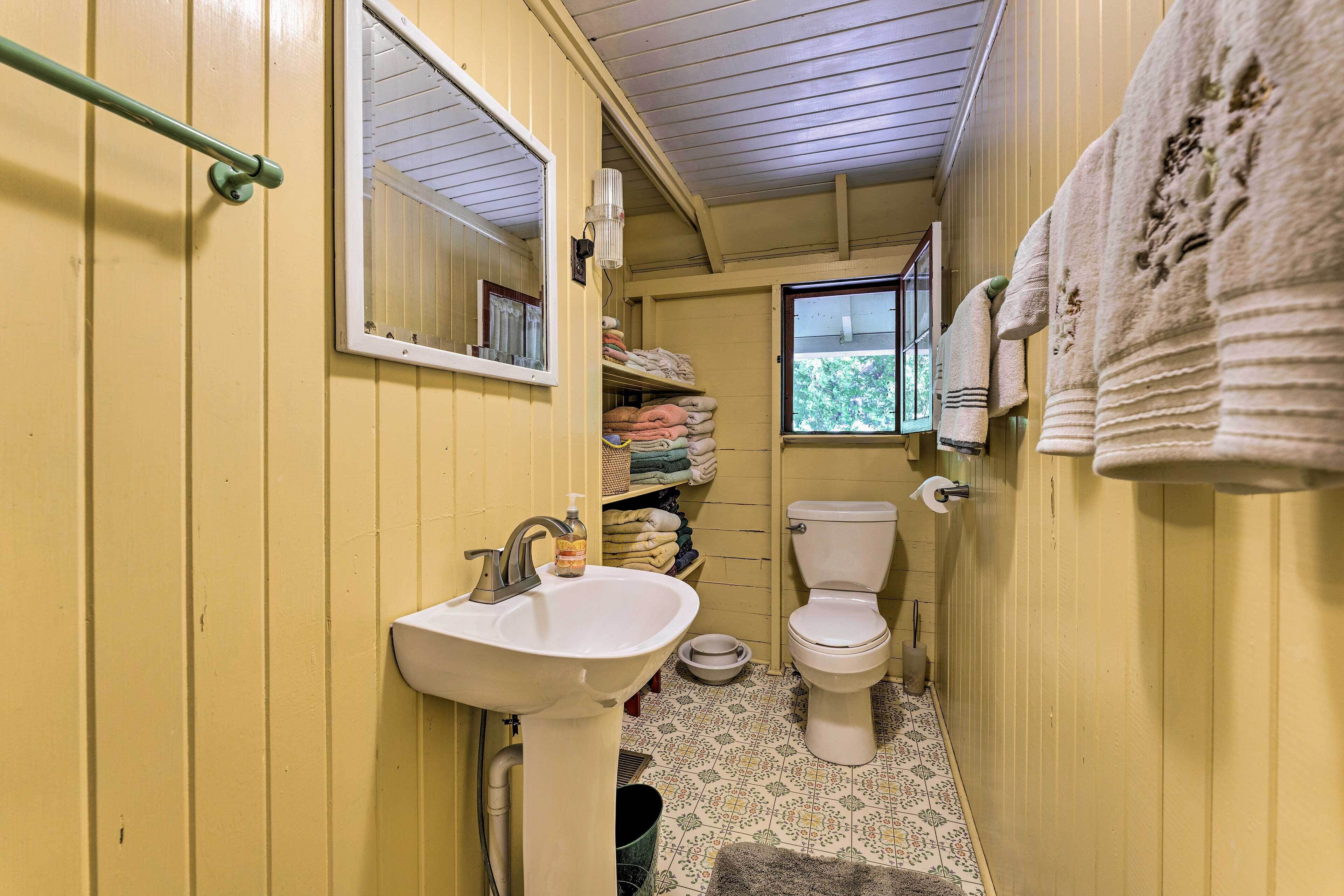 A small, narrow bathroom with a sink, toilet, and window.