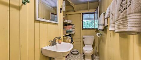 A small, narrow bathroom with a sink, toilet, and window.