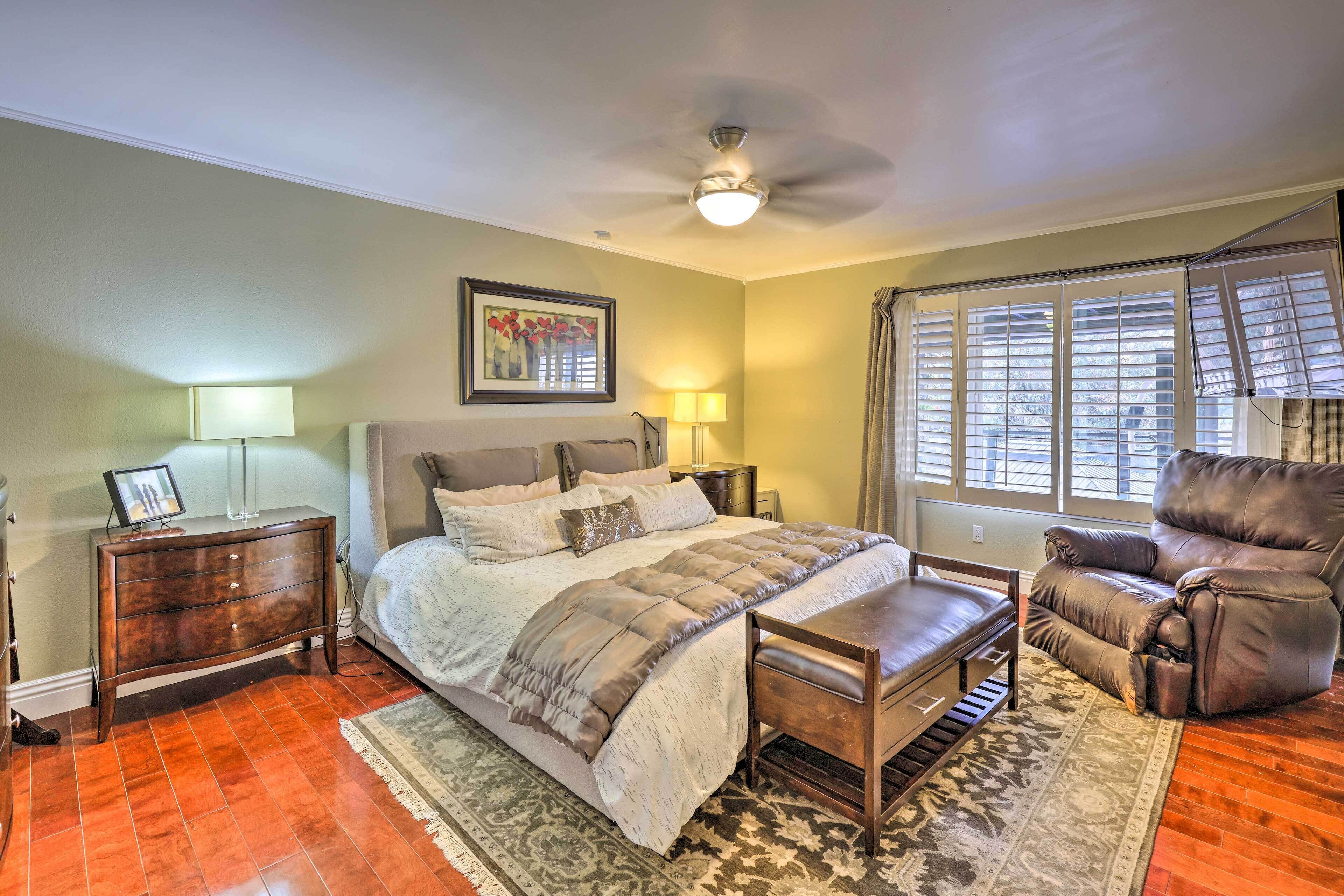 A bedroom with a bed, a desk, a chair, a dresser, and a window with blinds.