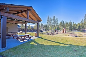 A covered picnic area with picnic tables and a building with a sloped roof.