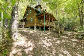 A wooden cabin with a balcony, surrounded by trees in a forest.