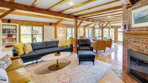 A spacious living room with a dark-colored sofa, a round coffee table, and a fireplace. - Spacious Kennebunkport Home w/ View, 2 Mi to Beach (Kennebunkport)