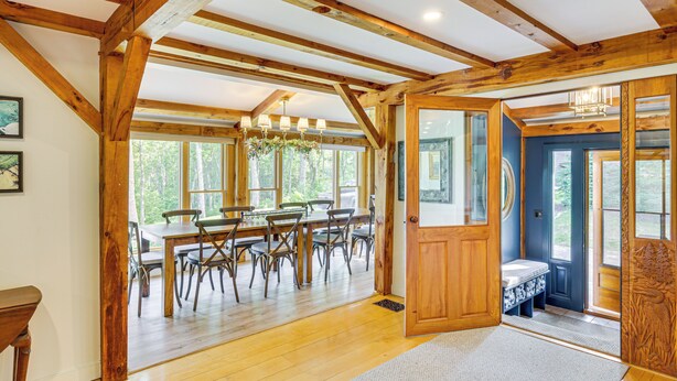 A spacious dining area with wooden beams, a chandelier, and a view of the outdoors. - Spacious Kennebunkport Home w/ View, 2 Mi to Beach (Kennebunkport)