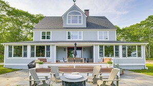 A two-story house with a covered patio, outdoor seating area, and a large window overlooking the yard. - Spacious Kennebunkport Home w/ View, 2 Mi to Beach (Kennebunkport)