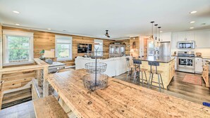 Uma cozinha moderna com armários de madeira, uma ilha central com banquetas e uma área de jantar com mesa de madeira.