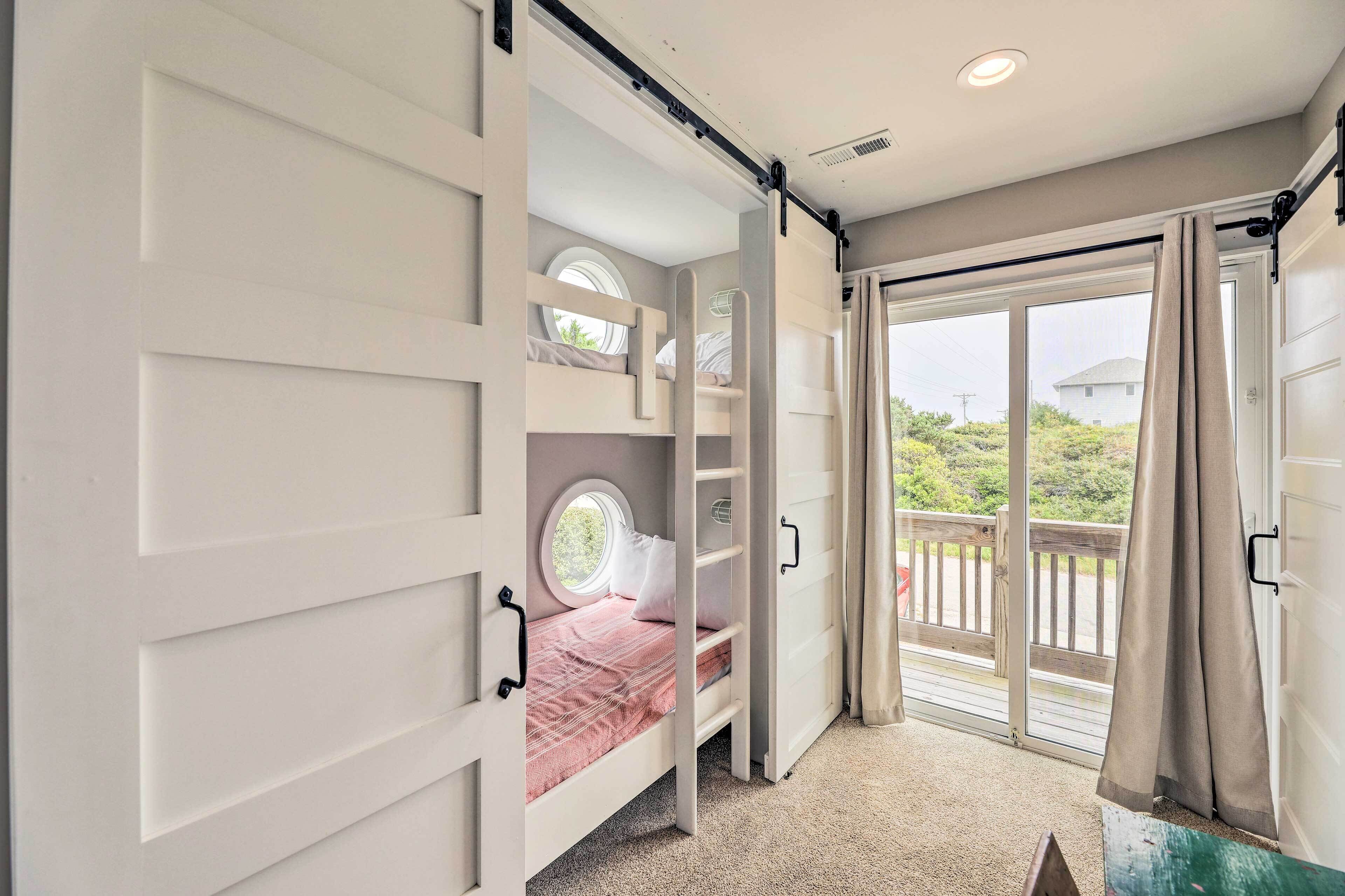 A bedroom with a bunk bed, a window, and a sliding door to a balcony.