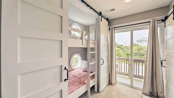 A bedroom with a bunk bed, a window, and a sliding door to a balcony.