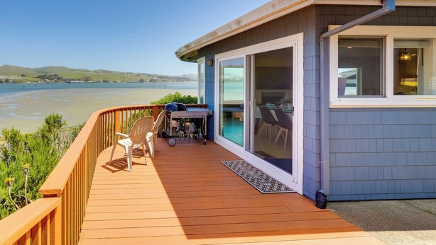 Une terrasse en bois offrant une vue sur un lac et des collines.