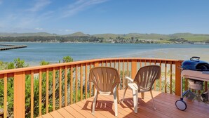 Une terrasse avec deux chaises et un barbecue, donnant sur un lac dont on aperçoit la rive au loin.