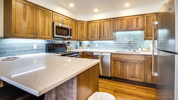 A modern kitchen with wooden cabinets, stainless steel appliances, and a marble countertop. - Hot Tub Access: Bright Breckenridge Condo (Breckenridge)