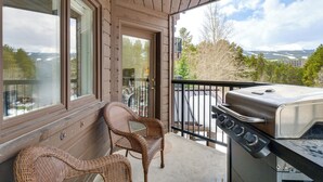 A balcony with wicker chairs, a grill, and a view of mountains. - Hot Tub Access: Bright Breckenridge Condo (Breckenridge)
