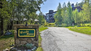 A sign for Woods Manor Condominiums with a stone base and a green and yellow signboard. - Hot Tub Access: Bright Breckenridge Condo (Breckenridge)