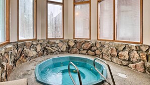 A hot tub with stone walls and large windows. - Hot Tub Access: Bright Breckenridge Condo (Breckenridge)