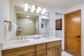 Un baño con dos lavamanos, un espejo grande y armarios de madera.