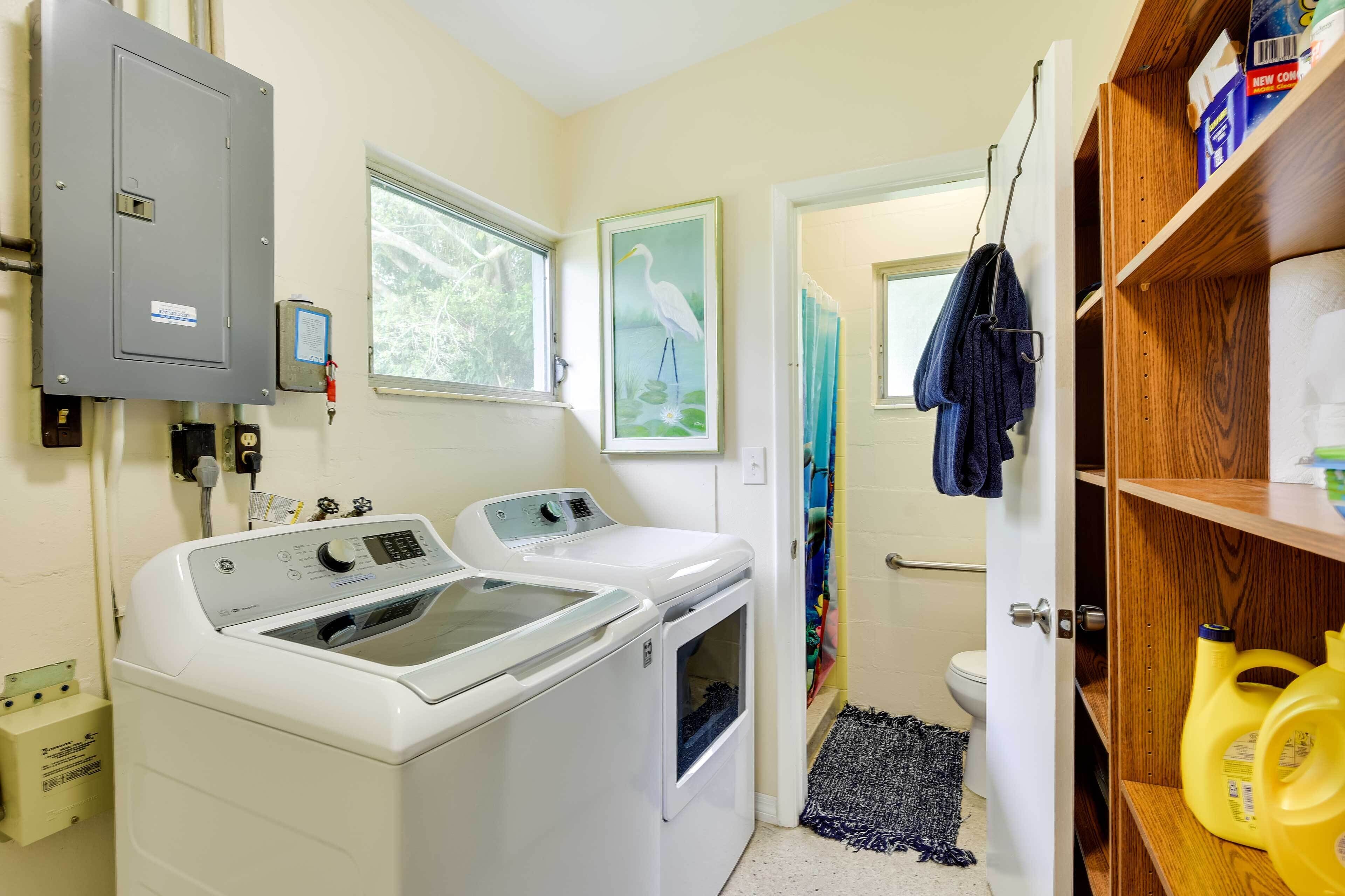 A laundry room with two front-loading washing machines, a utility meter, and a power outlet.